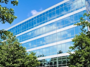 Modern office building with expansive windows against a clear sky.